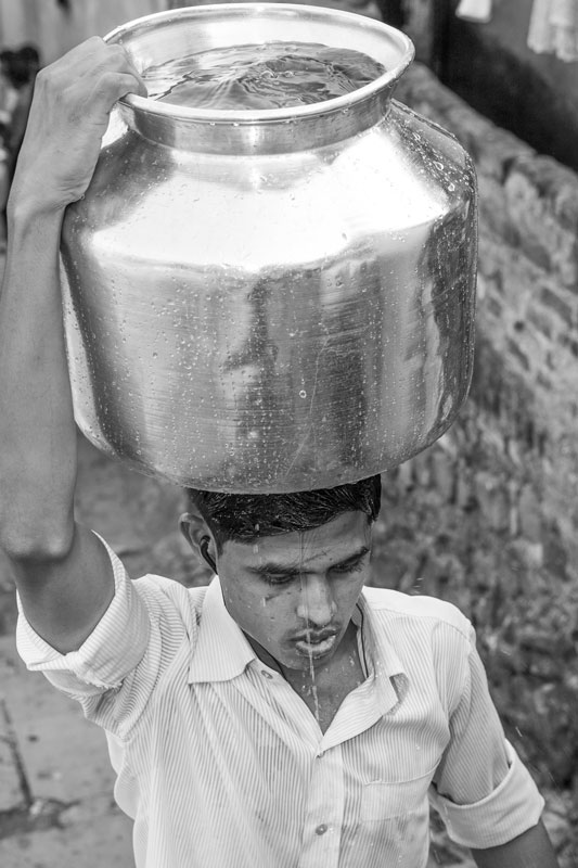 Men and Drinking Water Procurement - Drenched while hurriedly carrying a water pot on the head in Mumbai, Maharashtra
